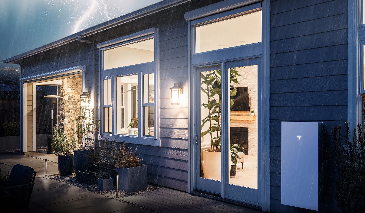 Tesla Powerwall on the wall of a house at night in the rain