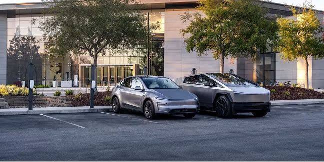 Two Tesla vehicles charging at wall-mounted charging stations in a commercial parking lot outside an office building