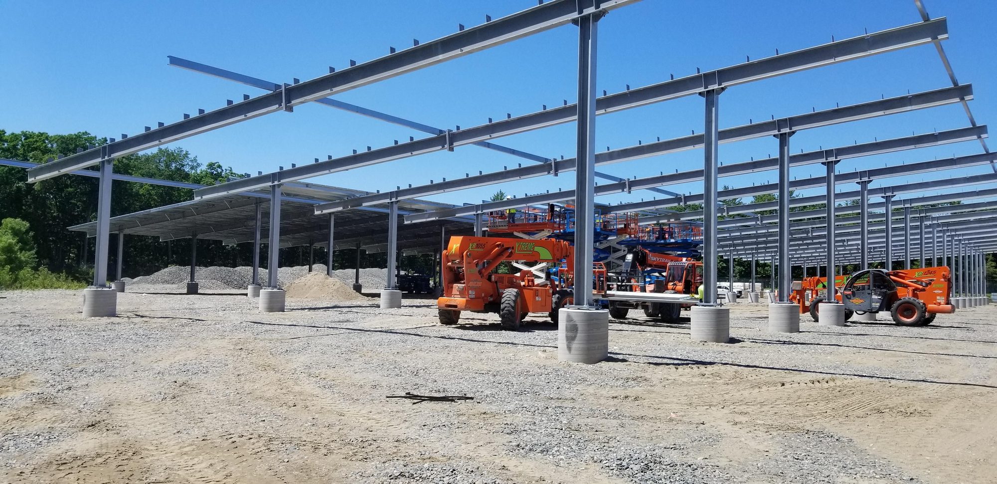 Galvanized steel solar carport frames under construction with lift equipment on site